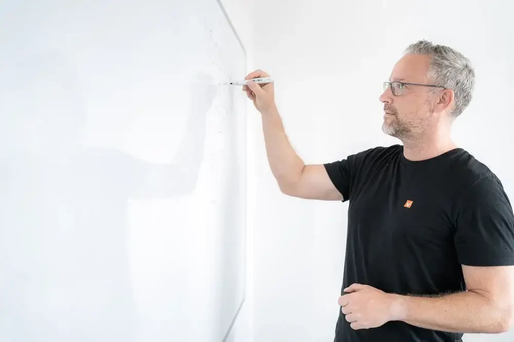 Mann steht am Whiteboard in HubSpot Agentur und setzt den Stift an