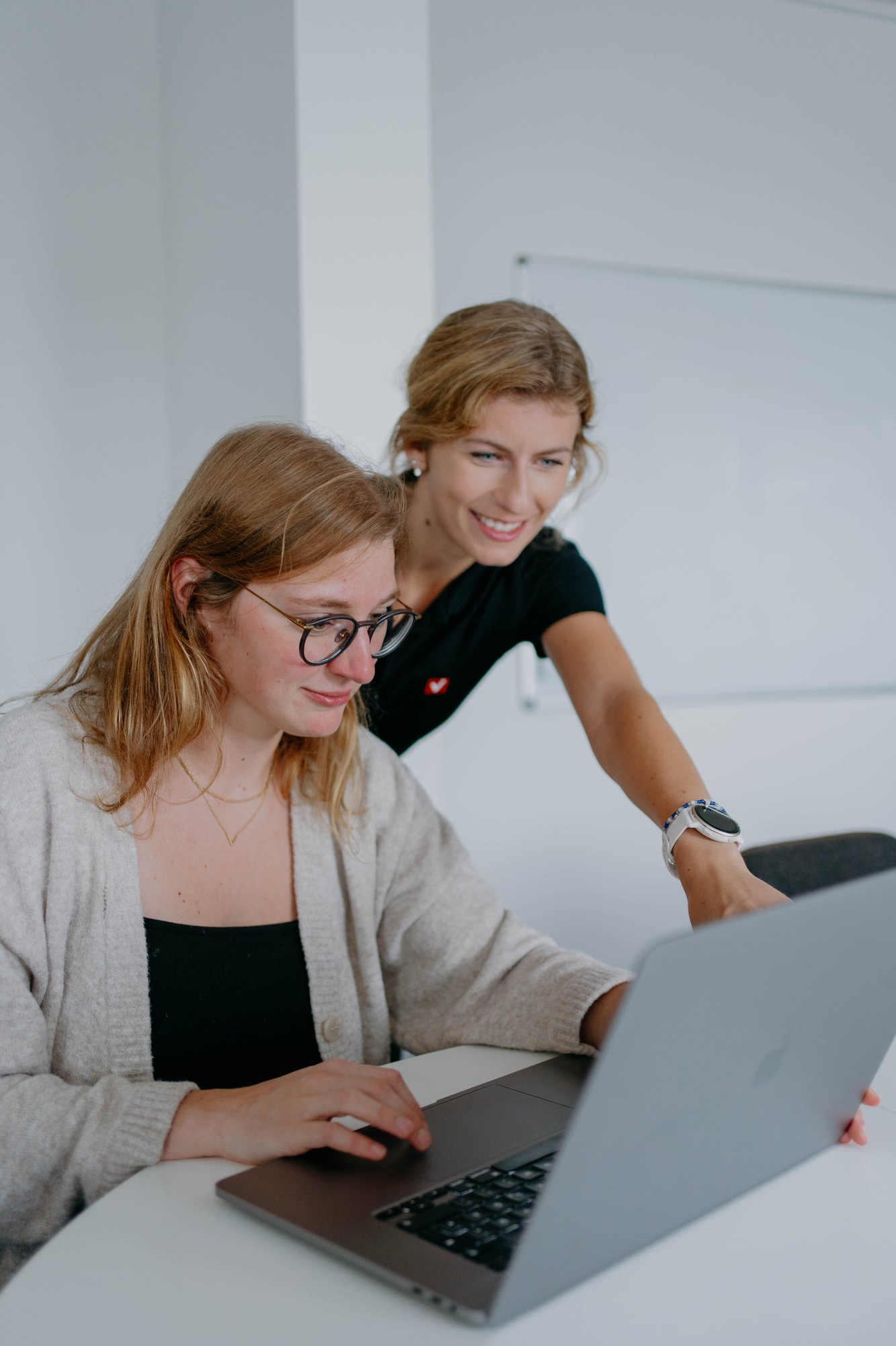 Zwei viminds Mitarbeiterinnen auf einen Laptop schauend