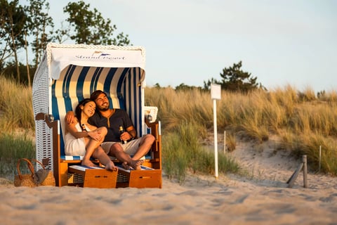 Paar sitzt im Strandkorb vom Strandresort Markgrafenheide am Strand vor den Dünen