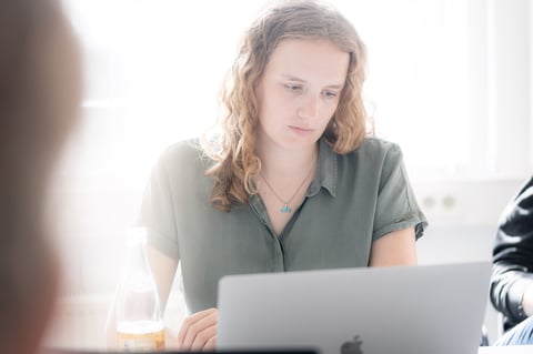 Frau sitzt am MacBook und plant Marketing Maßnahmen